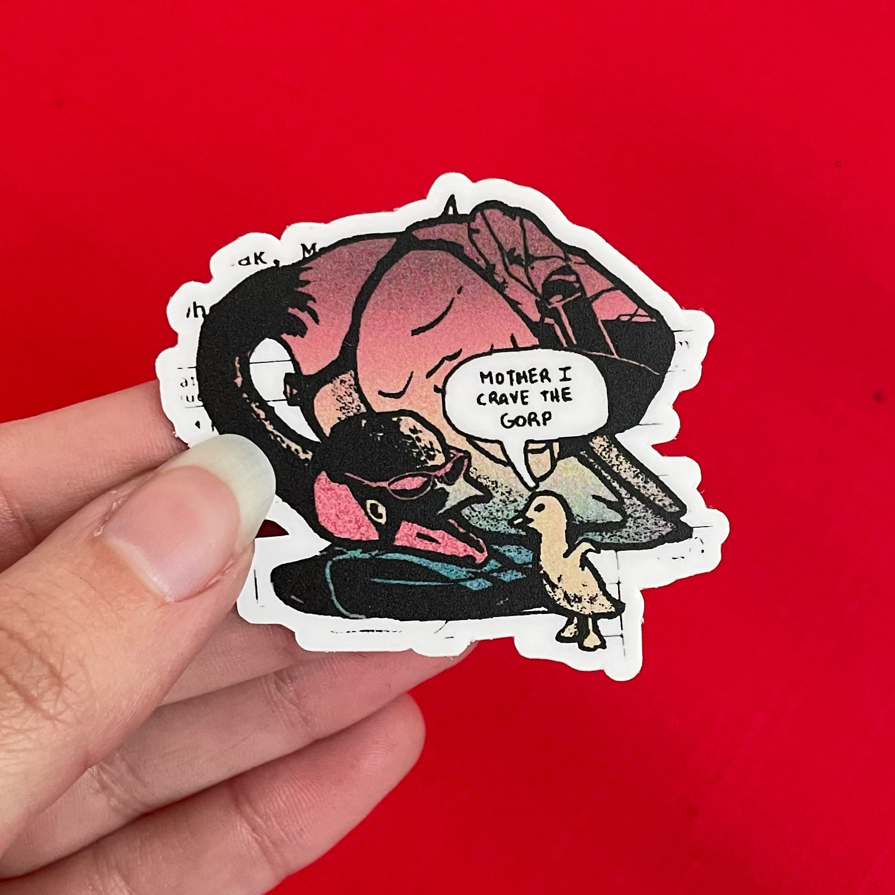 A hand holding a die-cut sticker featuring a comic-style illustration of a mother goose and her young, set against a solid bright red background.